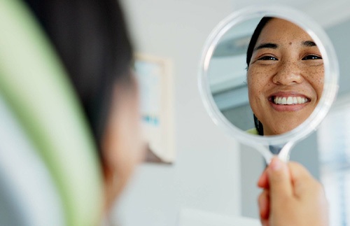 Woman smiling at reflection in dentist office