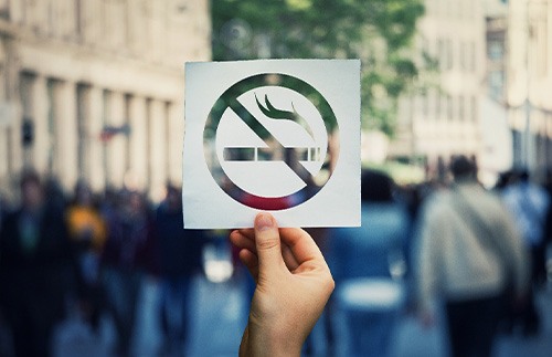 A hand holding a ‘No Smoking’ sticker