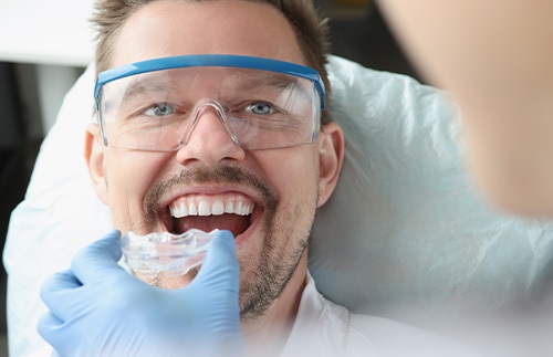 A man receiving a transparent plastic mouthguard from his dentist