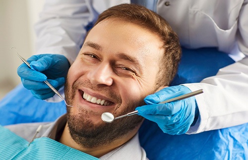 A smiling, bearded man receiving a dental checkup