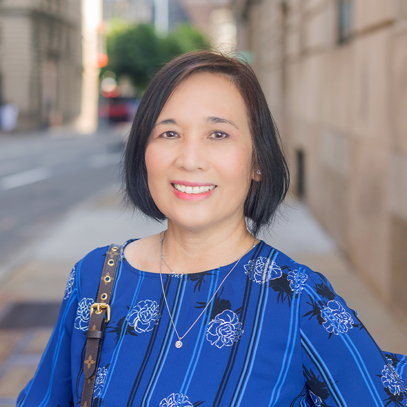 Woman in blue shirt smiling on city street