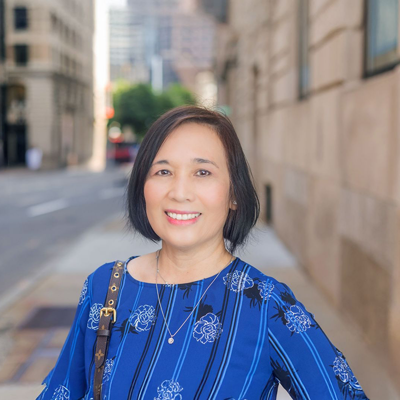 Woman in blue shirt smiling on city street