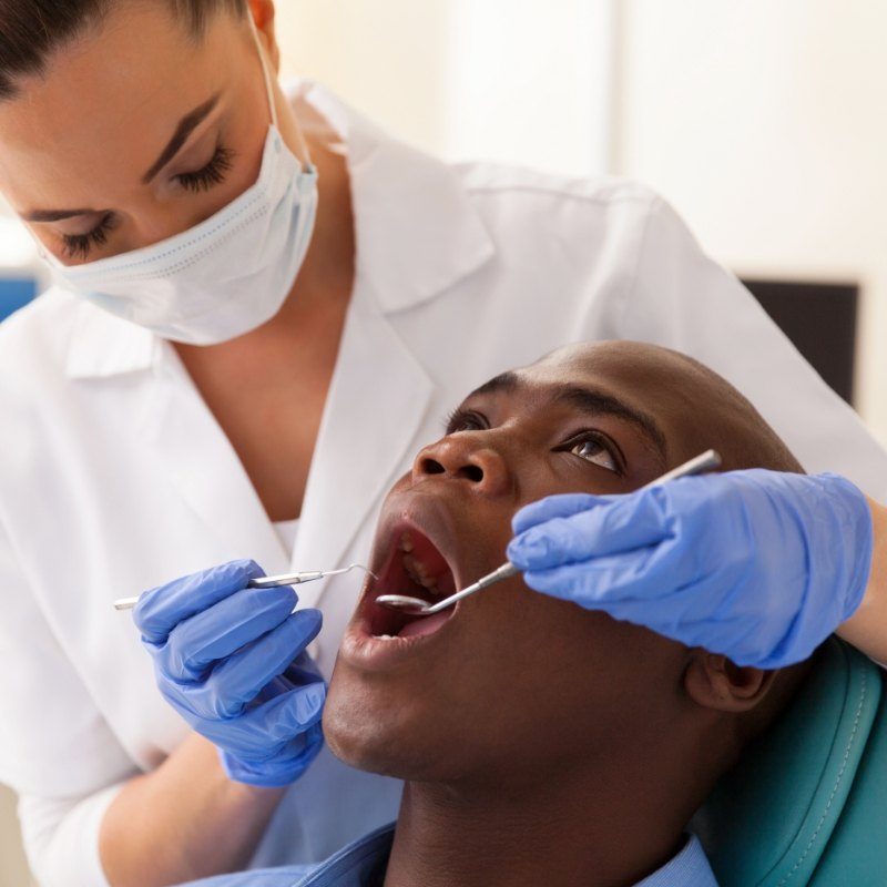 Female dentist examining male patients teeth