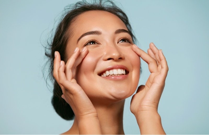 Woman smiling and touching her face