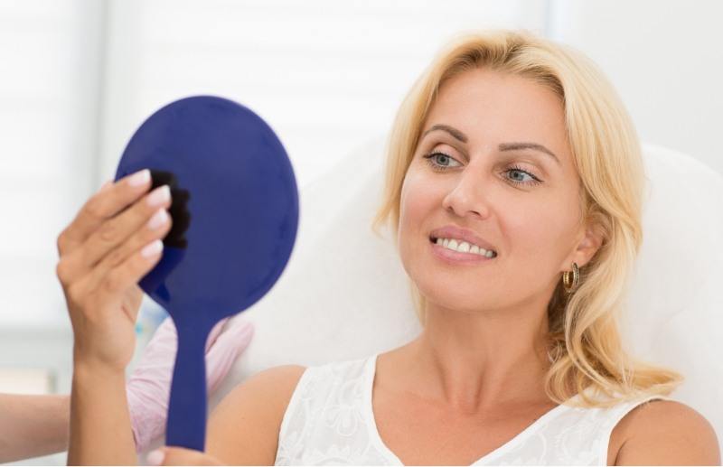 Woman checking smile in handheld mirror