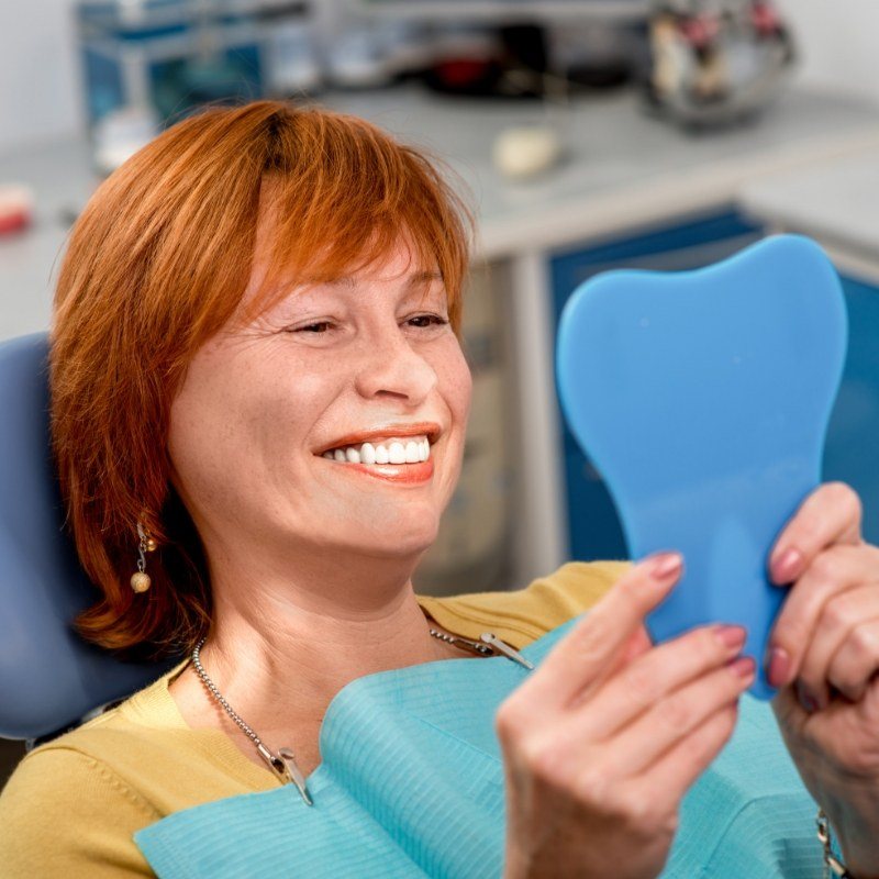 Red haired woman looking at smile in mirror