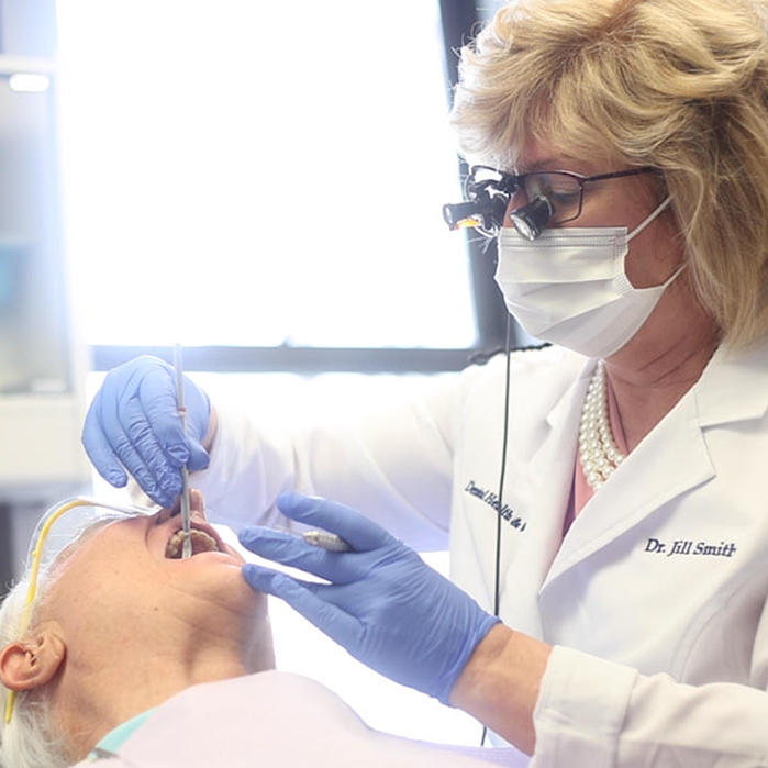 Dentist with glasses treating a patient