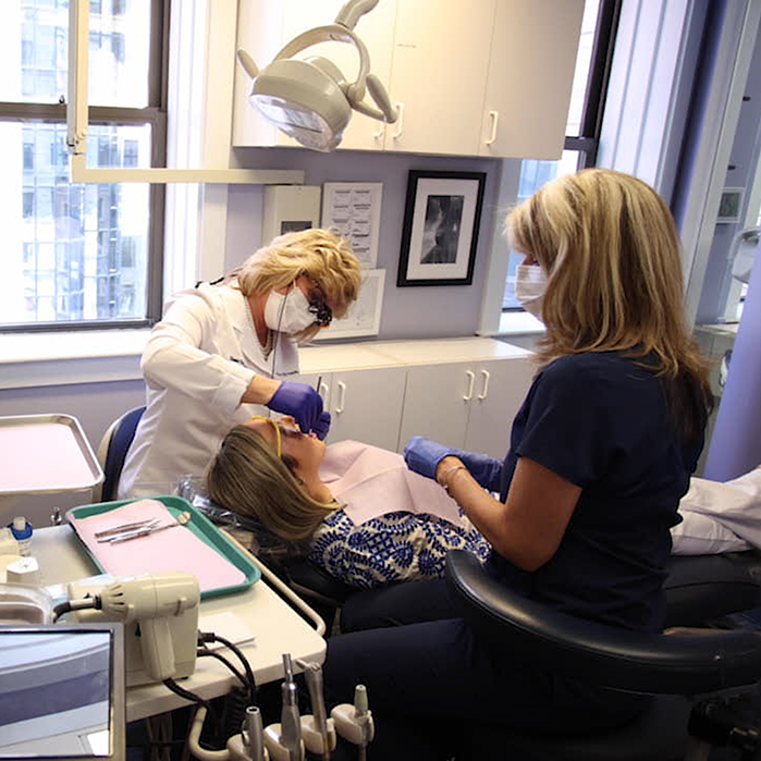 Two dentists performing cosmetic bonding on patient