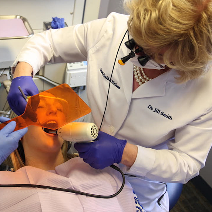 Dentist performing teeth whitening on patient