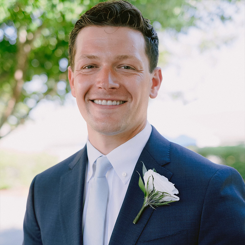 Man with glasses smiling and touching face