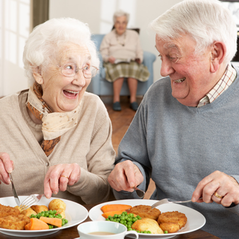 Two older individuals eating a meal together