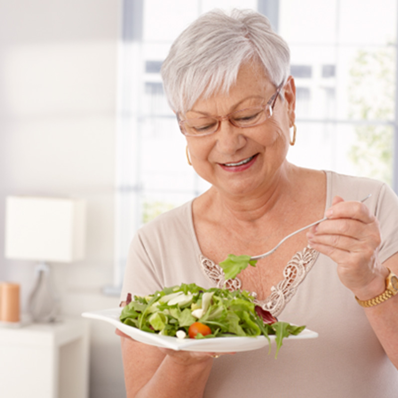 Older woman enjoying a salad with her dentures