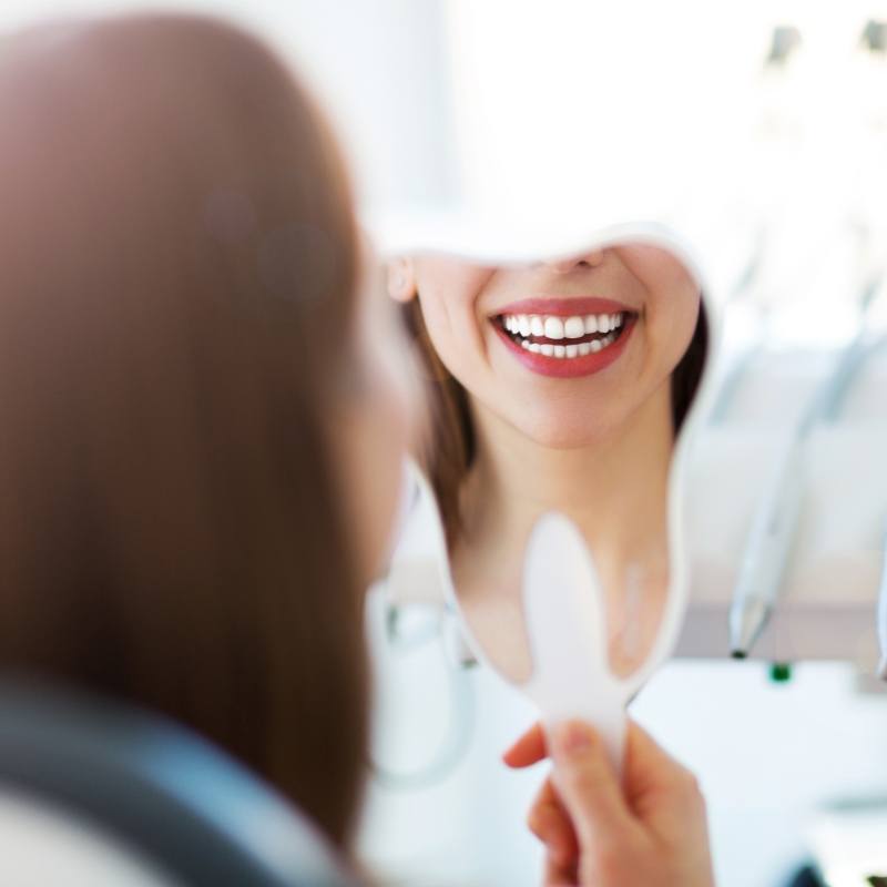 Womans smile reflected in handheld mirror