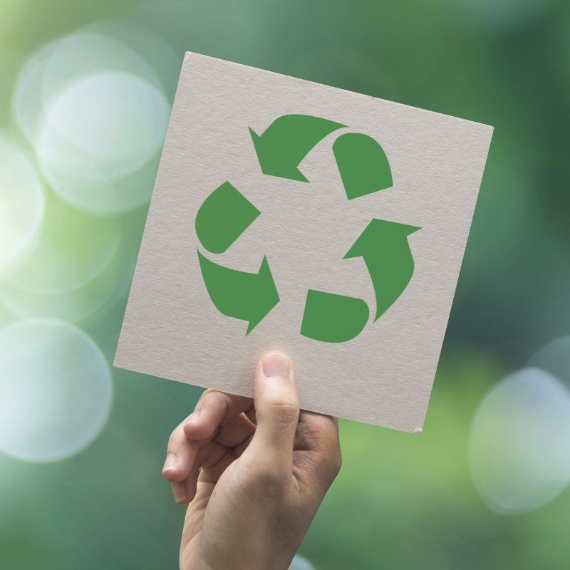 Holding up a sign with green recycling symbol