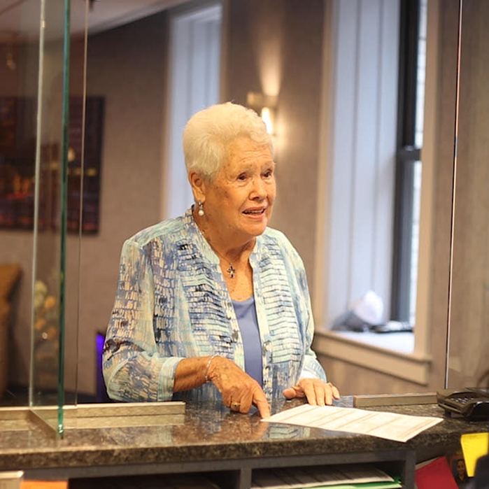 Woman standing at front desk of dental office with form