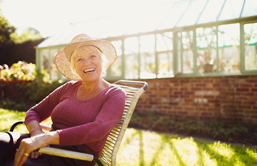 Woman sitting outside wearing hat and smiling