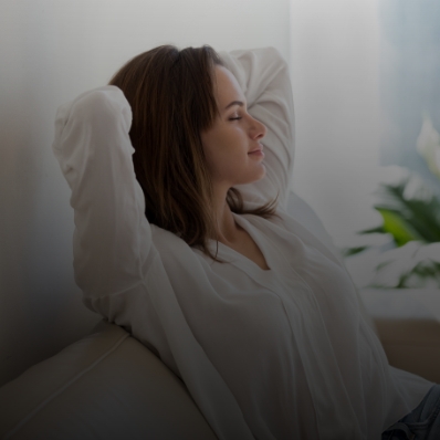 Woman relaxing at home with hands behind head