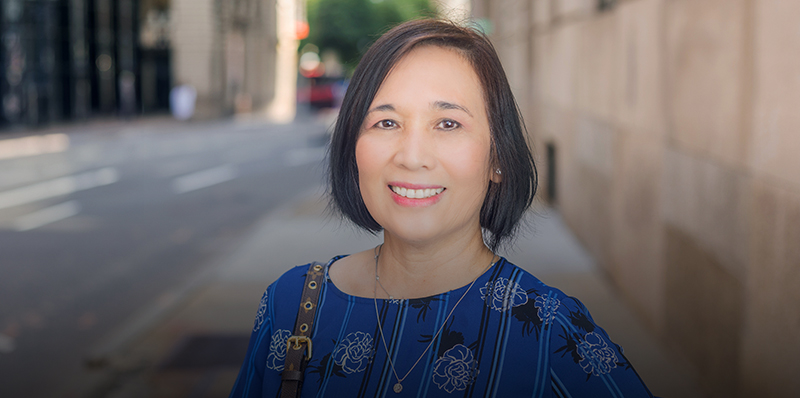 Woman in blue shirt smiling outside in the city