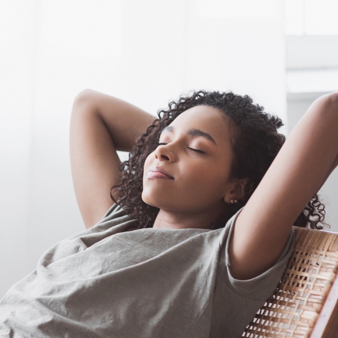 Woman relaxing at home with hands behind head