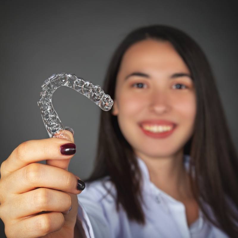 Woman holding a clear Invisalign aligner