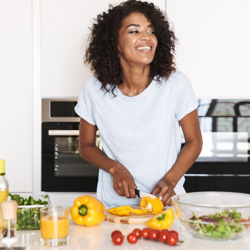 Woman in white shirt chopping up vegetables