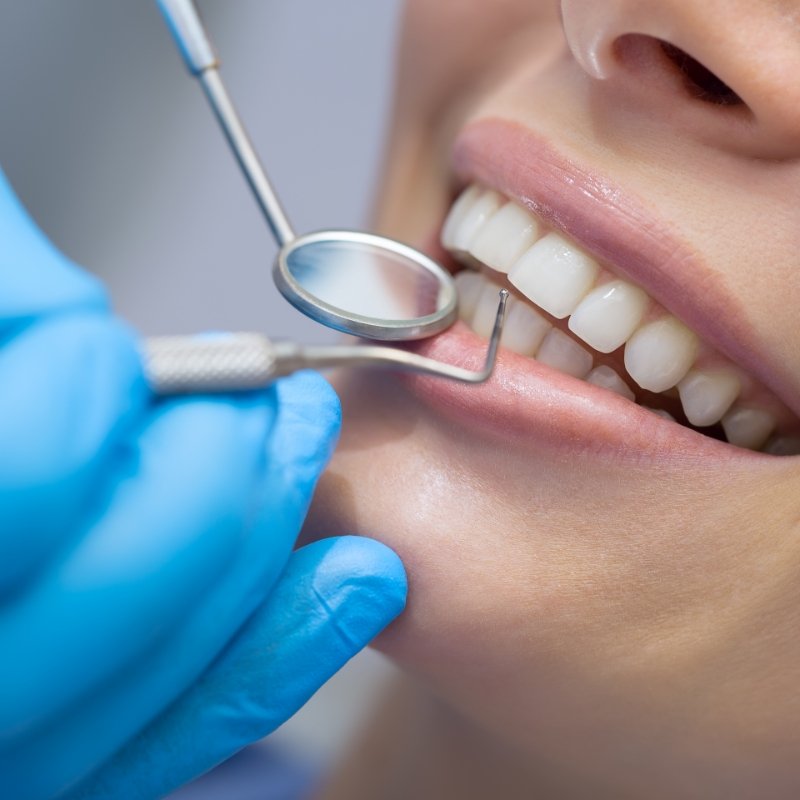 Dental mirror and explorer in front of teeth