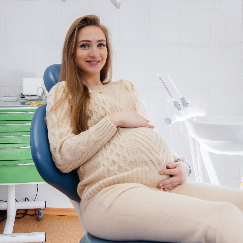 Pregnant woman in sweater sitting in dental chair