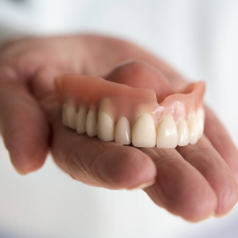 Close up of hand holding dentures