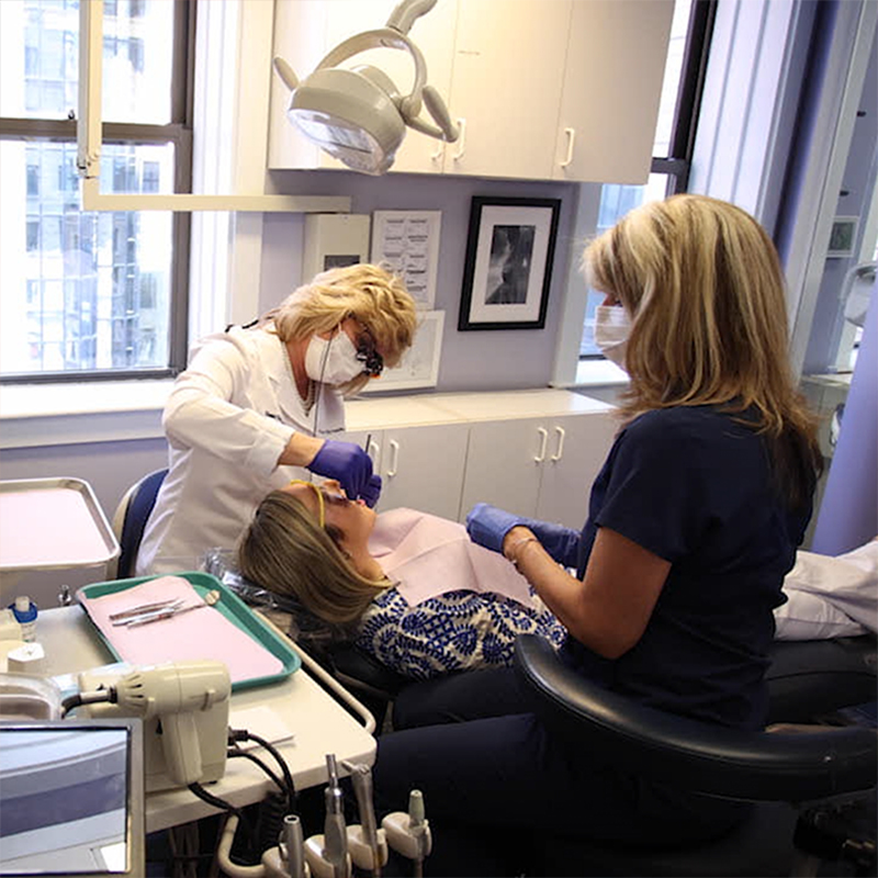 Woman in red shirt laughing in dental chair