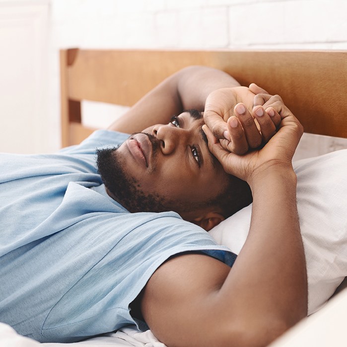 Tired man lying awake in bed