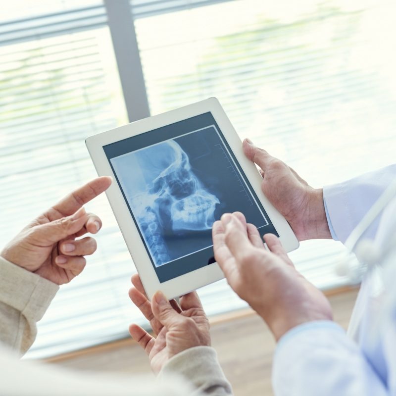 Dentist showing patient an X ray on a tablet