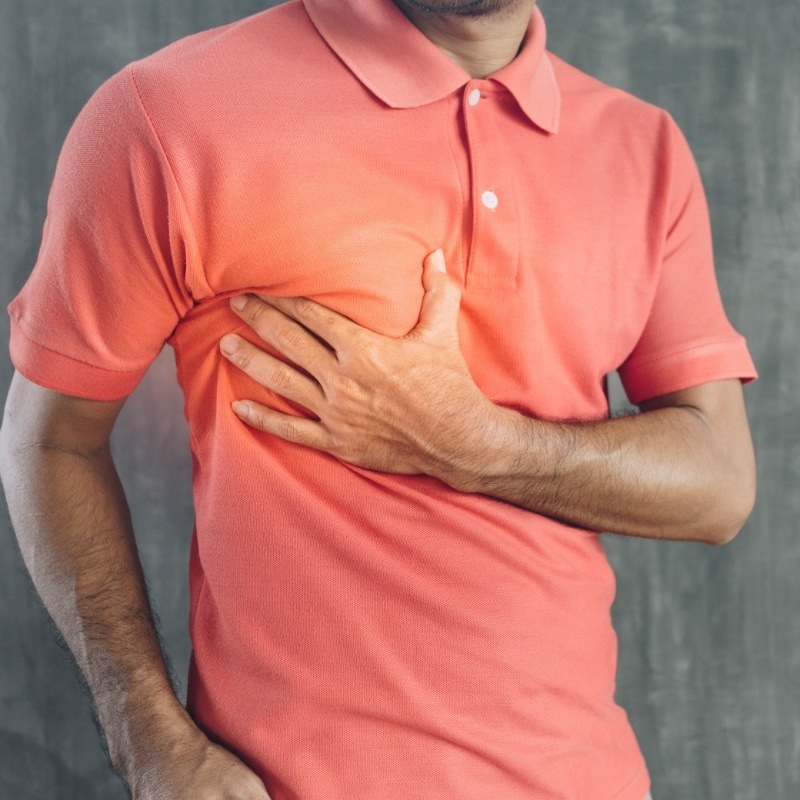 Man in peach colored shirt with hand over heart