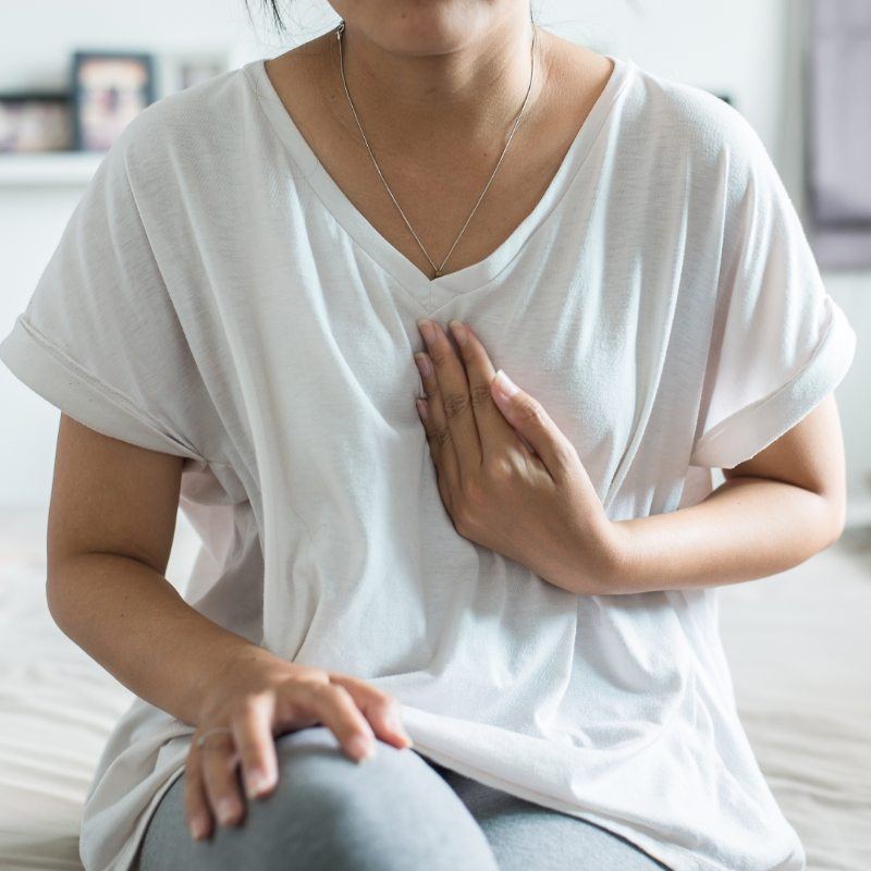 Woman in white shirt with hand on chest