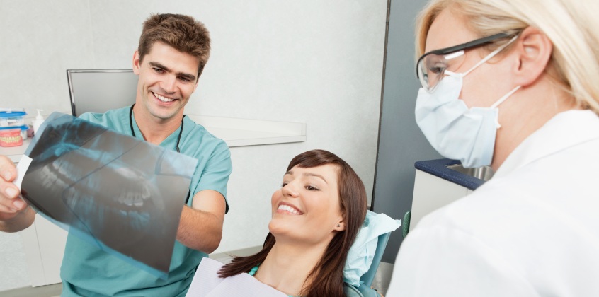 patient, nurse, and dentist examining dental x rays