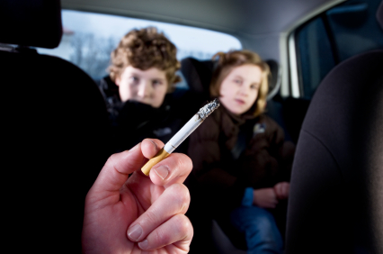 adult smoking with kids in the backseat of car